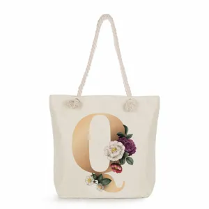 Close-up of canvas tote bag featuring elegant gold letter Q and floral print details.