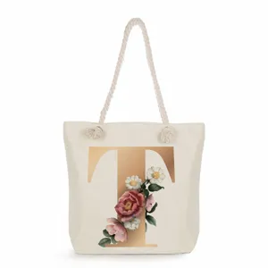 Detailed view of canvas tote bag with golden letter T and vintage floral print design.