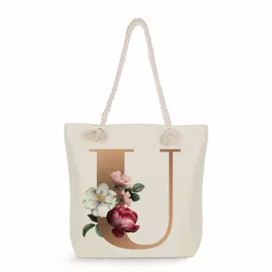 Canvas tote bag detail showing gold letter U print, vintage floral design and rope handle.