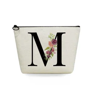 Close-up detail of canvas makeup bag featuring elegant letter M and floral print design.