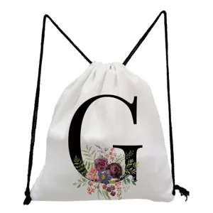 Close-up detail of white drawstring backpack featuring black letter G and watercolor floral print.