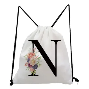 Close-up detail of the white drawstring backpack featuring a black letter N and floral print.