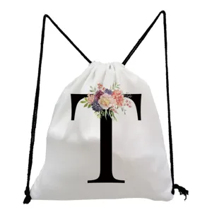 Close-up detail of white drawstring backpack featuring floral letter T print and black cords.