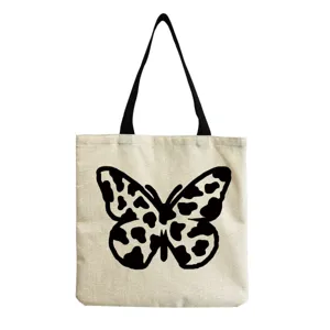 Close-up detail view of canvas tote bag featuring unique black cow print butterfly graphic design.