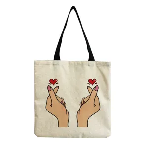 Canvas tote bag detail featuring a cute finger heart graphic print and sturdy black shoulder straps.
