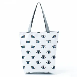 Casual large capacity canvas shoulder tote bag with trendy blue eye print, white background.