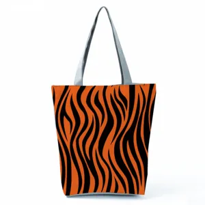 Detailed view showing the orange tiger stripe pattern and gray handle of canvas tote bag