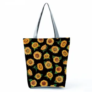 Stofftasche mit Sonnenblumen Print auf schwarzem Hintergrund und grauen Griffen fuer Damen.