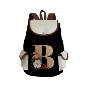 Close-up detail of canvas backpack featuring floral letter B print and brown leather trim.