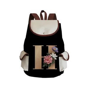 Detailed view of black canvas backpack with letter H floral print, brown straps and pocket.