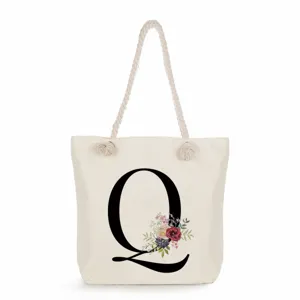 Beigefarbene Segeltuch Tragetasche mit Buchstabe Q und Blumenprint, ideal für Strand und Alltag.