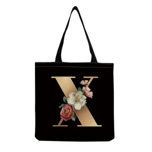 Black canvas tote bag featuring a chic gold letter X and vintage floral print for daily use.