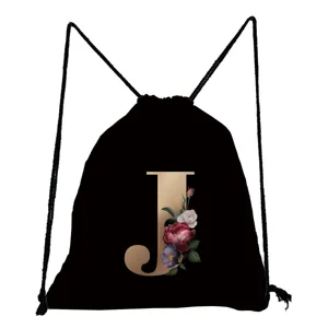 Nahaufnahme des schwarzen Turnbeutels mit goldener J-Buchstaben- und Blumen-Druckgrafik.