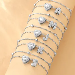Gros plan de la chevillère cœur en zircon argenté avec breloques de lettres brillantes.
