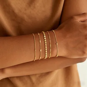 Set de pulseras doradas en capas de acero inoxidable, joyería de cadena minimalista elegante.