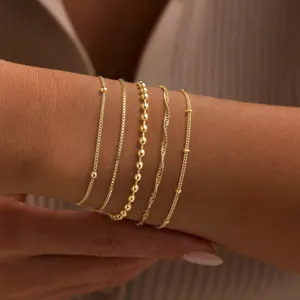 Primer plano detallado del juego de pulseras de cadenas doradas delicadas, estilo elegante.