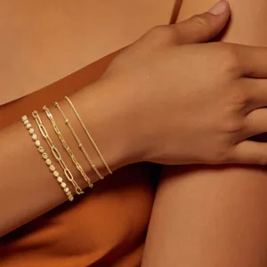 Vista de cerca detallada de pulseras apilables doradas con delicadas texturas de cadenas.