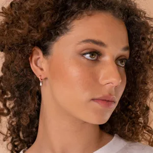 Gros plan détaillé d'une petite boucle d'oreille en or rose avec un zircon.