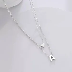 Gros plan détaillé du beau collier double argenté avec cœur et pendentif lettre A.