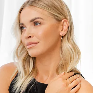 Gros plan d'élégantes boucles d'oreilles créoles dorées avec pendentif en zircone et bague.