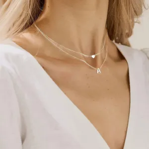 Collier double couche doré avec pendentifs cœur et lettre A, bijoux minimalistes et élégants.