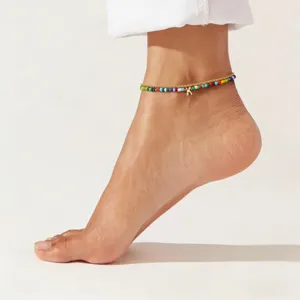 Detailed close-up of the multi-layer colorful seed bead anklet with a delicate letter charm.