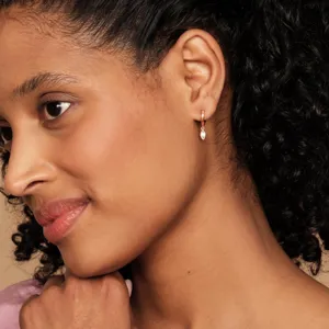 Gros plan détaillé des boucles d'oreilles créoles pendantes avec zircone sur oreille.