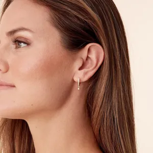 Vue détaillée de boucles d'oreilles créoles dorées avec zircon et pendentif perle.