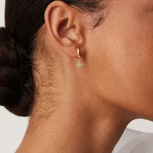 Gros plan détaillé de boucles d'oreilles créoles dorées avec un pendentif œil magique.