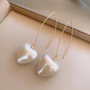 Gros plan détaillé de boucles d'oreilles pendantes dorées avec des perles brillantes.