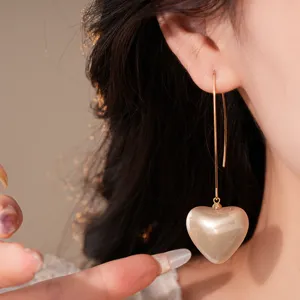 Gros plan détaillé de boucles d'oreilles cœur perle longue frange dorée vintage, bijoux chic.