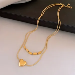 Collier double en acier inoxydable doré avec pendentif cœur et perles géométriques.