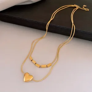 Gros plan d'un collier double en acier inoxydable doré avec un joli pendentif cœur.