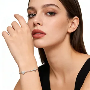 Close-up detail of silver bracelet featuring heart pendant with letter M and delicate cross charm.