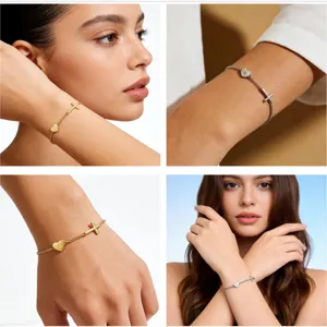 Close-up detail of the fashion letter A heart and cross charm bracelet on model wrist.