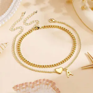 Gold double layer anklet detailed view showing heart and letter A charms on beach style setting.