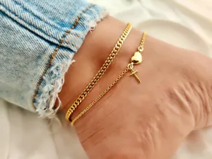 Gold-plated double layer anklet featuring a heart and cross pendant with curb chain detail.