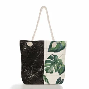 Grand sac cabas en toile avec marbre noir et imprimé de feuilles vertes tropicales.