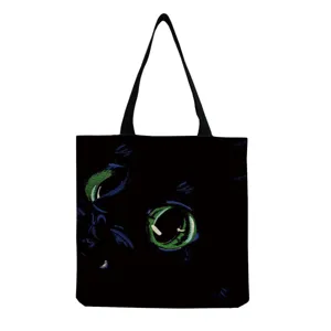Close-up detail of black canvas tote bag featuring glowing green cat eyes print, casual style.