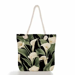 Λεπτομέλεια τσάντας ώμου από καμβά με floral σχέδιο, χοντρά σχοινιά, μαύρο φόντο.