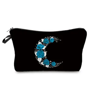 Black cosmetic bag detail showing blue rose crescent moon print, compact zipper travel pouch.