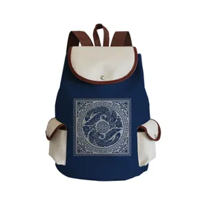 Detailed view of blue canvas backpack with traditional Chinese phoenix pattern and beige pockets.