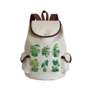 Détail de sac à dos en toile avec imprimé de plantes vertes et bordure en cuir marron.