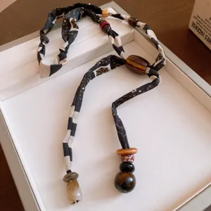 Primer plano detallado de un collar de tela con patrón retro y cuentas de madera y acrílico.