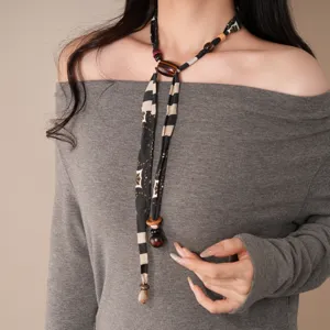 Primer plano detallado de un collar de tela vintage con patrones geométricos y abalorios.