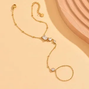 Dettaglio del bracciale da mano dorato con zirconi brillanti e anello coordinato.