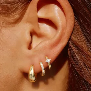 Gedetailleerde close-up van trendy gouden huggie creolen oorbellen set met drie unieke ontwerpen.