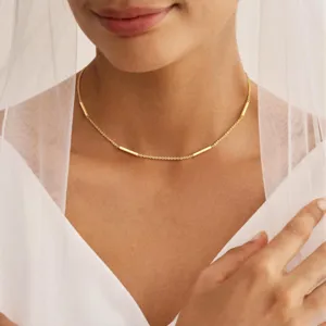 Minimalist gold-colored copper clavicle chain necklace featuring delicate tube charms worn on model.