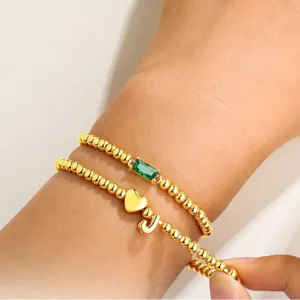 Bracciale di perline dorato a strati con zircone verde rettangolare e ciondolo cuore lettera J.