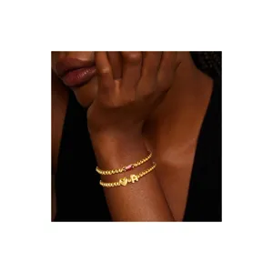 Set di bracciali di perle dorate con uno zircone rosso e un ciondolo con lettera.